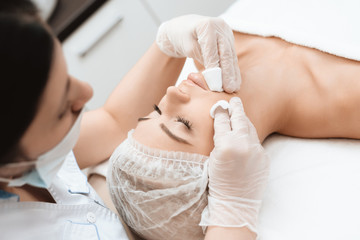 The doctor makes the girl a facial cleansing massage. The girl came to the procedure of laser hair removal.