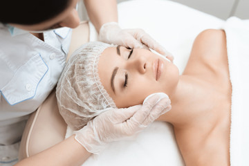 The doctor makes the girl a facial cleansing massage. The girl came to the procedure of laser hair removal.