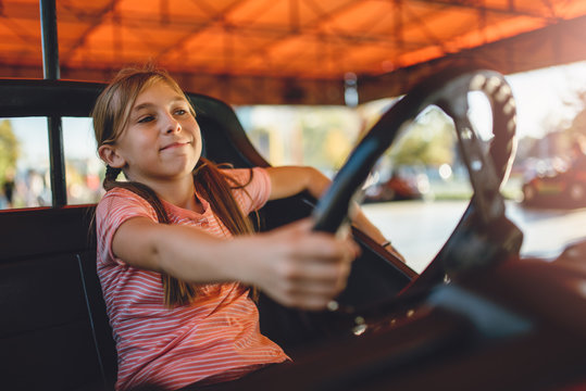 Girl driving electric cars in amusement park