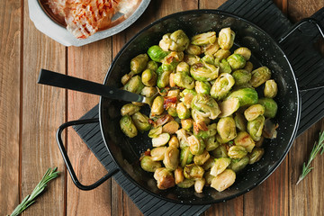 Frying pan with roasted Brussel sprouts and bacon on wooden table