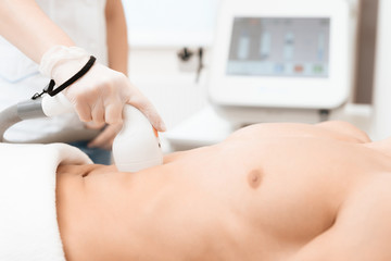 The man came to the procedure of laser hair removal. The doctor treats his stomach with a special...