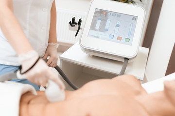 The man came to the procedure of laser hair removal. The doctor treats his stomach with a special apparatus.