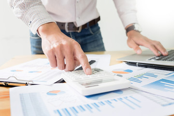 business men working on wooden desk(table) with notebook computer paper, pencil and hand in office, financial concept.