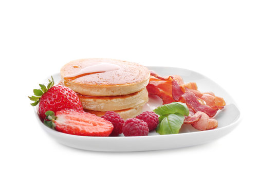 Tasty breakfast with pancakes, bacon and berries on white background