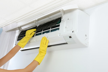 Young woman checking air conditioner at home