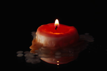 Wax candle burning down in darkness, closeup
