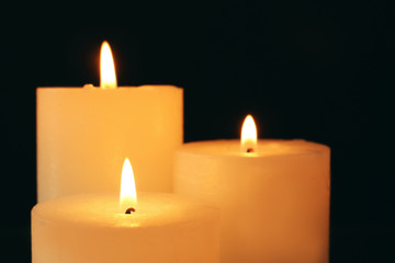 Fototapeta na wymiar Wax candles burning in darkness, closeup