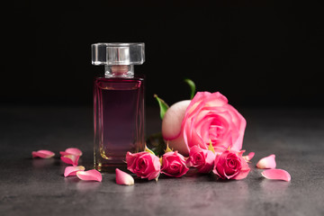 Bottle of perfume and roses on dark background