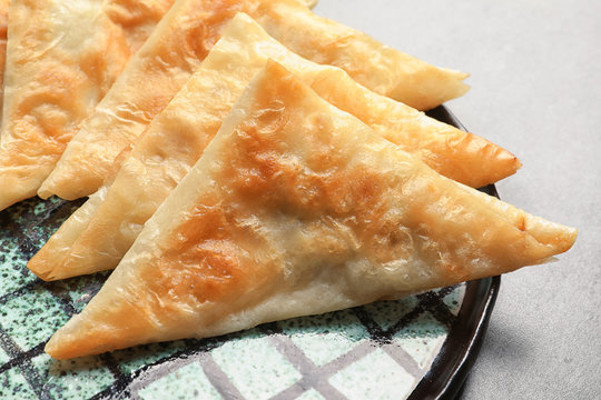 Plate with delicious samosas on grey background, closeup