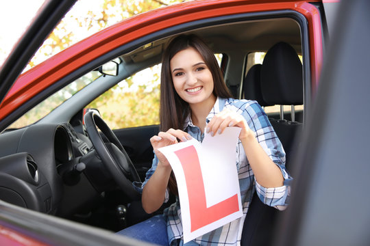 Happy Young Woman Tearing Learner Driver Sign In Car