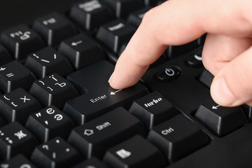 Woman pressing "Enter" button on computer keyboard, closeup