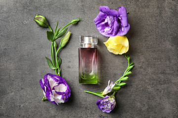 Bottle of perfume with flowers on grey background