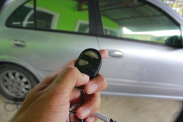 Checking tirHand of man holding and push key remote control of car parking 