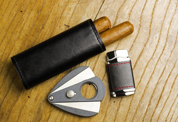 Leather case with cigars, lighter and cigar cutter on an wooden board