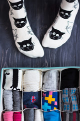 Feet selfie with black and white socks and a socks organizer on a dark background. Top view