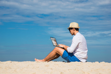 man sitting on the sea beach on line with notebook vedio call conference and chats with girlfriend who’s at home to keep in touch at all time the movement on each other