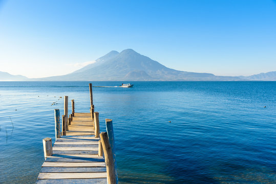 Wooden pier at Lake Atitlan on the shore at Panajachel, Guatemala. With beautiful landscape scenery of volcanoes Toliman, Atitlan and San Pedro in the background. © Simon Dannhauer