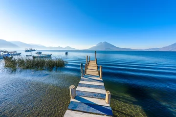 Foto op Canvas Wooden pier at Lake Atitlan on the shore at Panajachel, Guatemala.  With beautiful landscape scenery of volcanoes Toliman, Atitlan and San Pedro in the background. © Simon Dannhauer