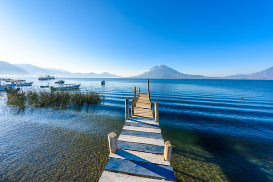 Wooden pier at Lake Atitlan on the shore at Panajachel, Guatemala.  With beautiful landscape scenery of volcanoes Toliman, Atitlan and San Pedro in the background.