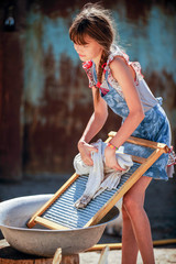 The farmer's daughter is washing his father's shirt in the yard