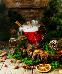 glass of hot mulled wine for the new year with ingredients for cooking, nuts and Christmas decorations