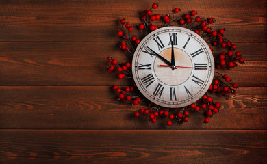 Clock with a Christmas wreath on a wooden wall