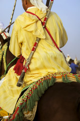 Obraz premium Horse Rider Wearing Moroccan Traditional Clothes Carrying His long arm gun During The Gunpowder PLay or Tbourida In Arabic which is a traditional exhibition celebrated In Morocco.