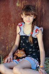 The girl is playing with red newborn pigs of the Duroc breed. The concept of caring and caring for animals.