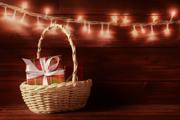 Gift boxes in basket over glowing garland