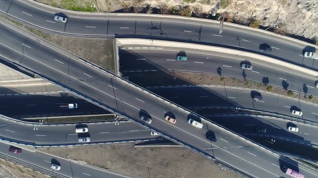 Aerovideo: unmanned aircraft flying over free interstate expressway with machines at spring day. The modern architecture of curvy autoban, many different winding turn. Casual lifestyle in megapolis