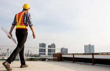 Professional Foreman wearing safety helmet hold blueprint while walking on the building deck