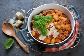 Potato gnocchi with meat sauce and parmesan served in a bowl on a metal cooling rack, studio shot, selective focus