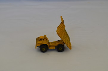 A yellow toy dump truck dumping.