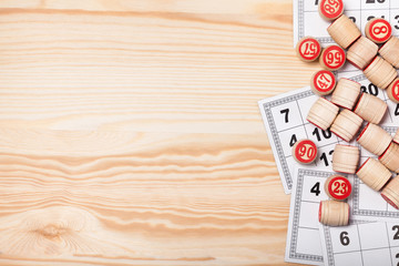 Bingo lotto on wooden background with copy space. Balls with bingo numbers, bingo cards. Flat lay.