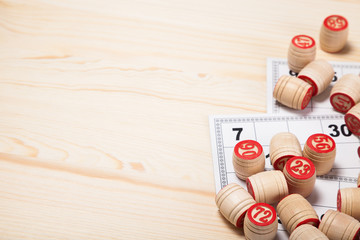 Bingo lotto on wooden background with copy space. Balls with bingo numbers, bingo cards. Flat lay.