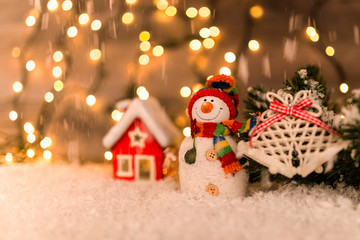 Christmas decoration on a wooden background with snowman, snow and lights in the background