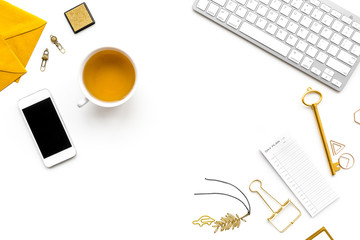 Office desk in trendy gold color. Glittering stationery near cup of tea and keyboard on white background top view copyspace