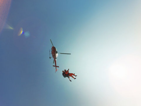 Low angle view of tandem skydiving jump from a helicopter  against sunlit blue sky