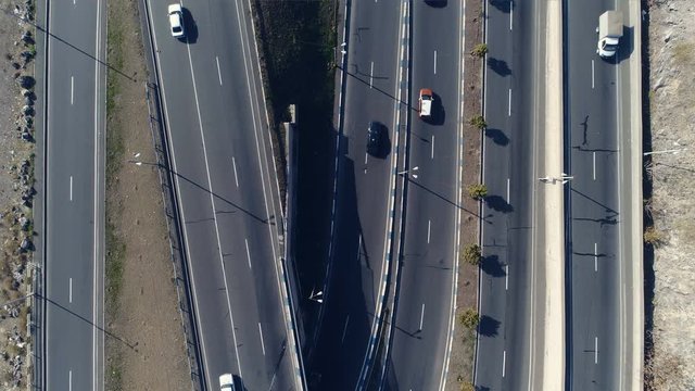 Aerovideo: unmanned aircraft flying over free interstate expressway with machines at summer day. The modern architecture of curvy autoban, many different winding turn. Casual lifestyle in megapolis