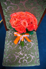 wedding bouquet with red flowers on a chair with a ring.