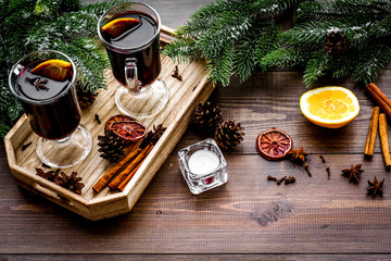 Warm mulled wine with citrus and spices for winter evening near spruce branch on dark wooden background