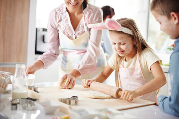 Girl with mother and brother easter baking at kitchen counter