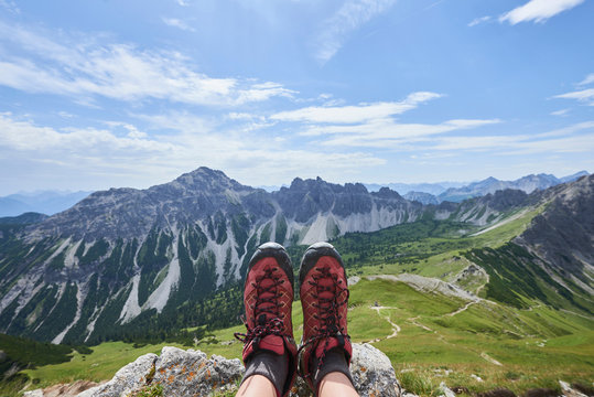 Personal perspective of female hiker's hiking boots over valley in Tannheim mountains, Tyrol, Austria