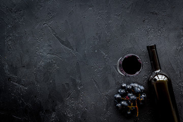 Drink wine concept. Bottle, glass, grape on black background top view copyspace