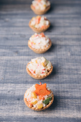 Crab salad tarts on wooden background. Christmas holiday buffet table served by snacks.  Line of canape