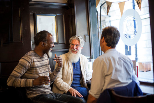 Three mature men, sitting together in pub, talking