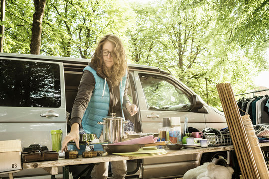 Female stall holder placing second hand goods on stall at forest flea market