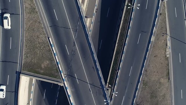 Aerovideo: unmanned aircraft flying over free interstate expressway with machines at autumn day. The modern architecture of curvy autoban, many different winding turn. Casual lifestyle in megapolis