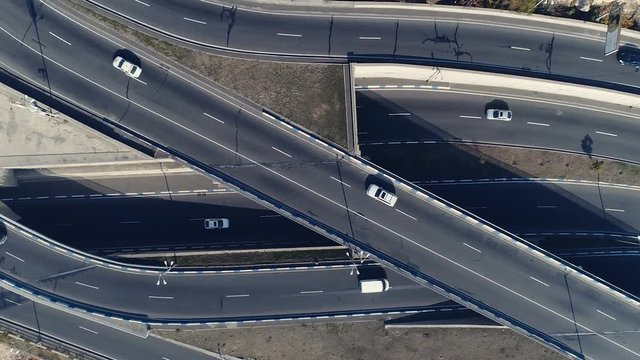 Aerovideo: unmanned aircraft flying over free interstate expressway with machines at summer day. The modern architecture of curvy autoban, many different winding turn. Casual lifestyle in megapolis