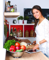 Young woman using a tablet computer to cook in her kitchen